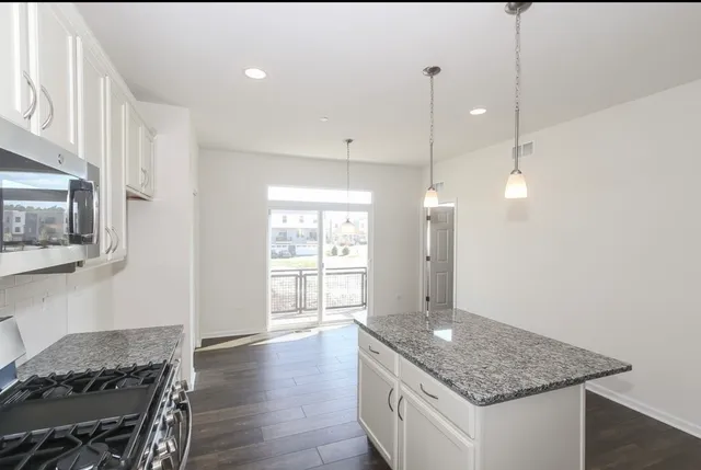 a kitchen with stainless steel appliances granite countertop a sink a stove and a wooden floors