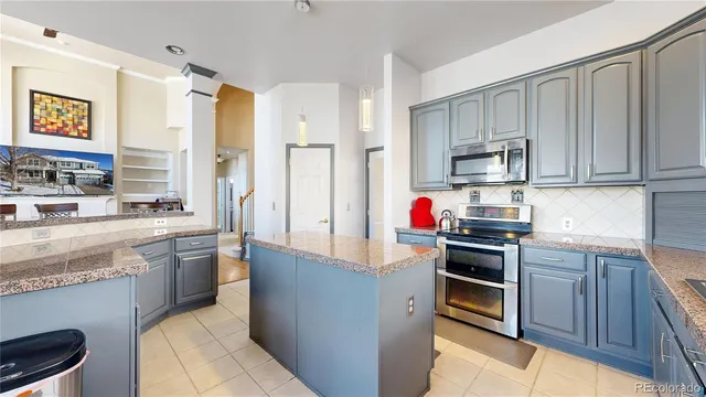 a living room with furniture a large window and stainless steel appliances