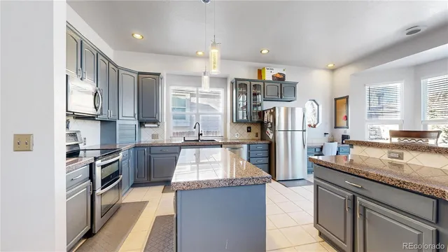 a kitchen with stainless steel appliances kitchen island granite countertop a refrigerator and microwave