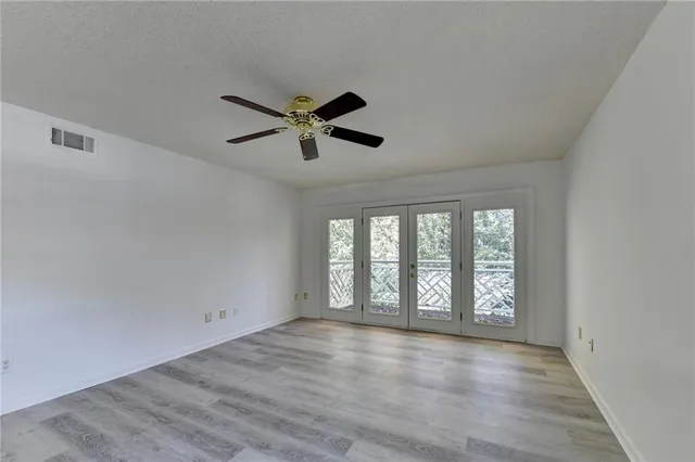 a view of an empty room with a window and wooden floor