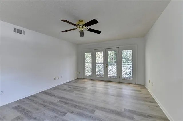 an empty room with a chandelier fan and windows