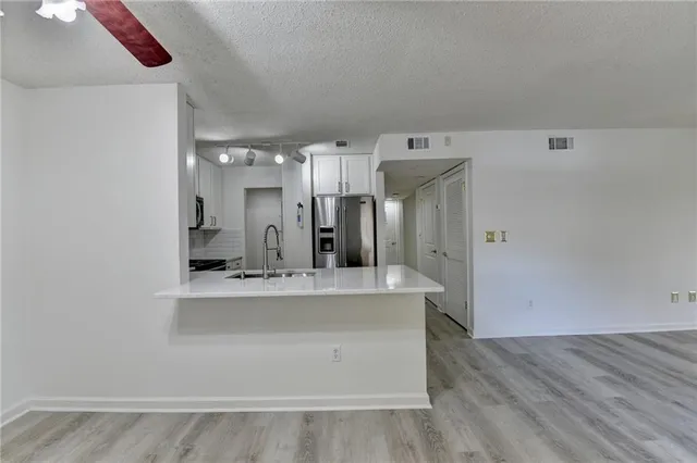 an empty room with a chandelier fan and windows