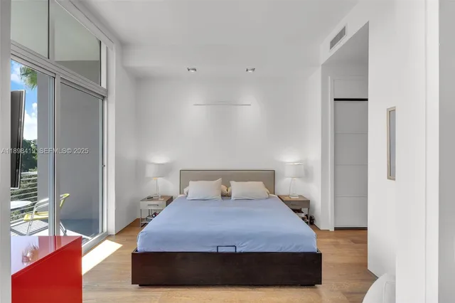 a bedroom with furniture a flat screen tv and a floor to ceiling window