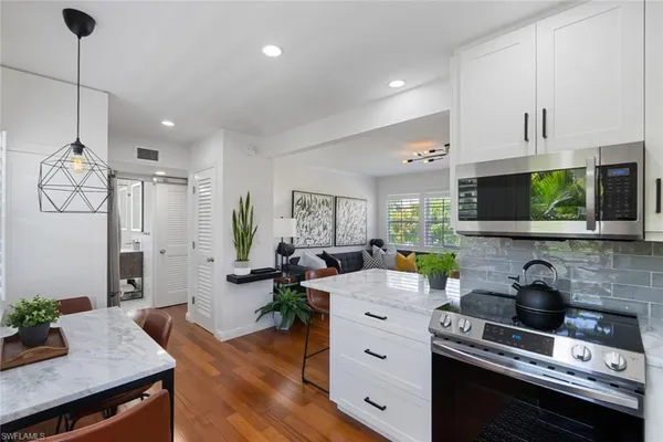 a kitchen that has a lot of cabinets stainless steel appliances and wooden floor