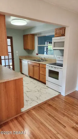 a kitchen that has a sink wooden cabinets and stainless steel appliances