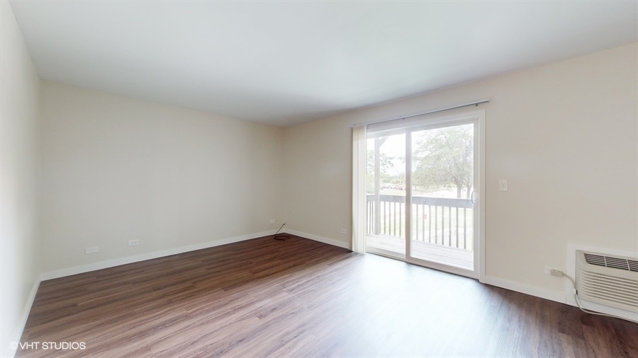 29-w542 Country Ridge Drive, Unit A Warrenville, IL 60555 - Photo 4 of 12 a view of an empty room with wooden floor and a window