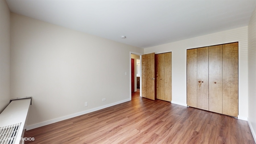 29-w542 Country Ridge Drive, Unit A Warrenville, IL 60555 - Photo 7 of 12 a view of an empty room with wooden floor and closet
