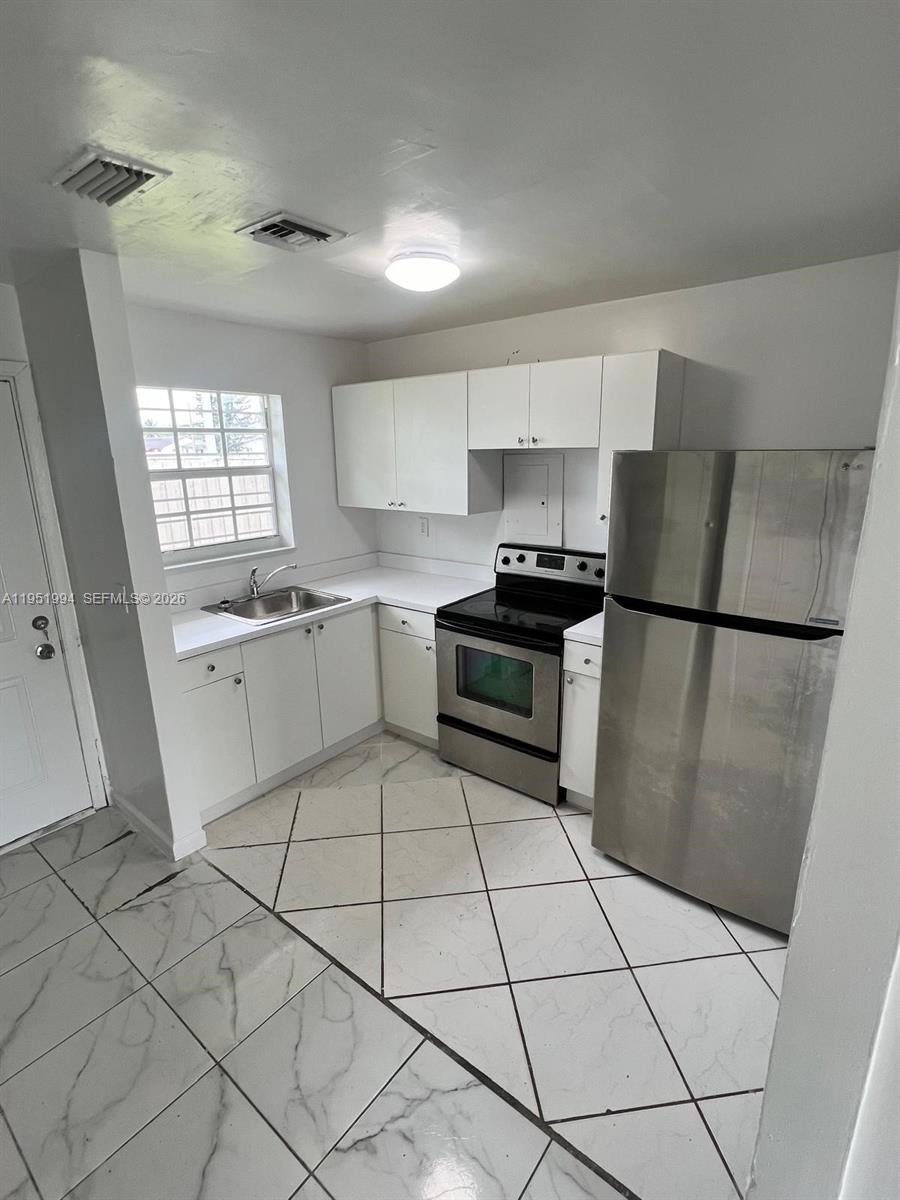 11535 Southwest 224th Street, Unit 2 Miami, FL 33170 - Photo 16 of 22 a kitchen with a sink a stove a refrigerator and cabinets