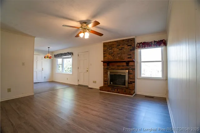 an empty room with wooden floor chandelier fan and windows