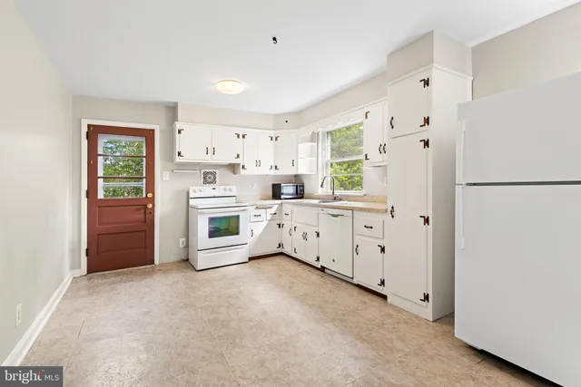 a large white kitchen with granite countertop a sink and dishwasher with a large window