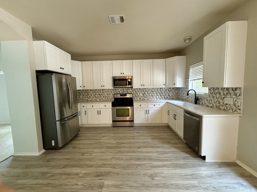 8301 Winterstein Drive Austin, TX 78745 - Photo 10 of 25 a kitchen with stainless steel appliances a refrigerator sink and white cabinets