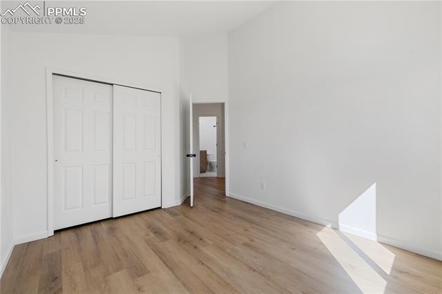 7827 Swiftrun Road Colorado Springs, CO 80920 - Photo 25 of 48 Unfurnished bedroom with light wood-style floors, a closet, high vaulted ceiling, and baseboards