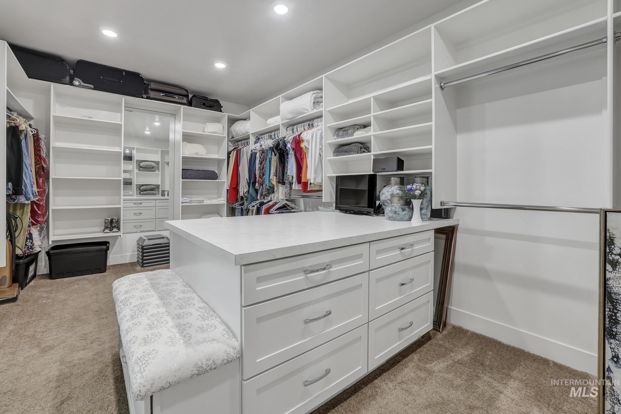 1937 Tamarack Loop Twin Falls, ID 83301 - Photo 37 of 50 Custom closet system featuring white built-in shelving, hanging rods, and a central island with drawers and a solid surface countertop