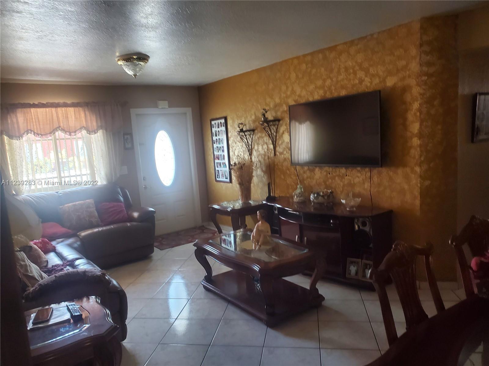 10953 West Okeechobee Road, Unit 101 Hialeah Gardens, FL 33018 - Photo 3 of 15 a living room with furniture and a flat screen tv