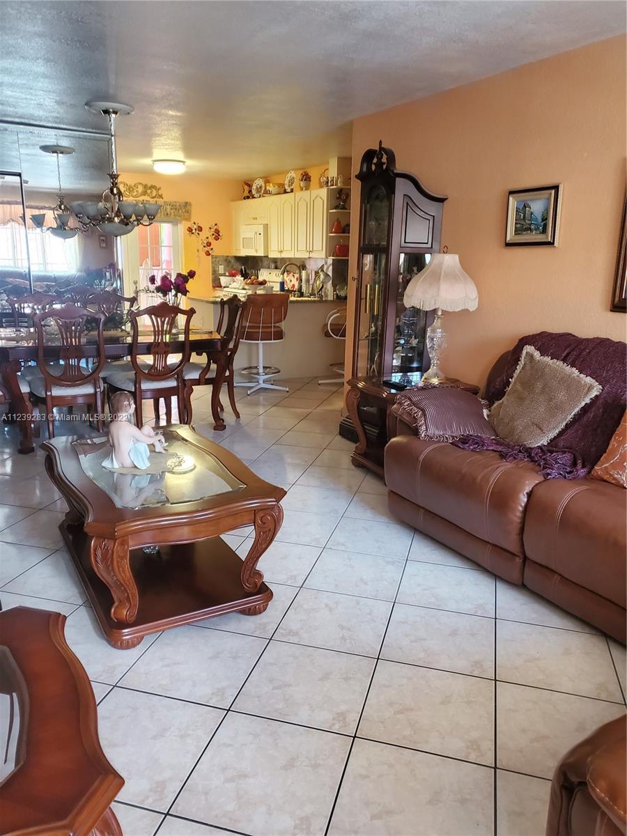 10953 West Okeechobee Road, Unit 101 Hialeah Gardens, FL 33018 - Photo 4 of 15 a living room with couches and a dining table with kitchen view