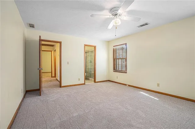 an empty room with a chandelier fan and windows