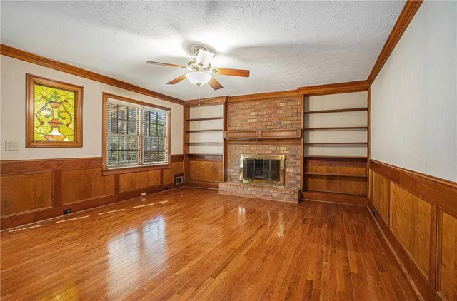 an empty room with wooden floor fireplace and windows