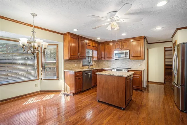 a kitchen with stainless steel appliances granite countertop wooden floors and white cabinets