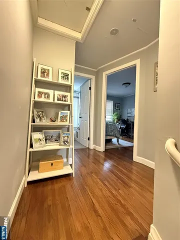 a view of front door and bedroom with wooden floor