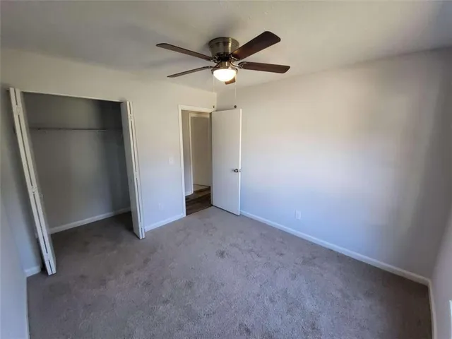 an empty room with closet and a ceiling fan