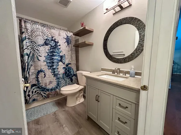 a bathroom with a granite countertop toilet a sink and a mirror
