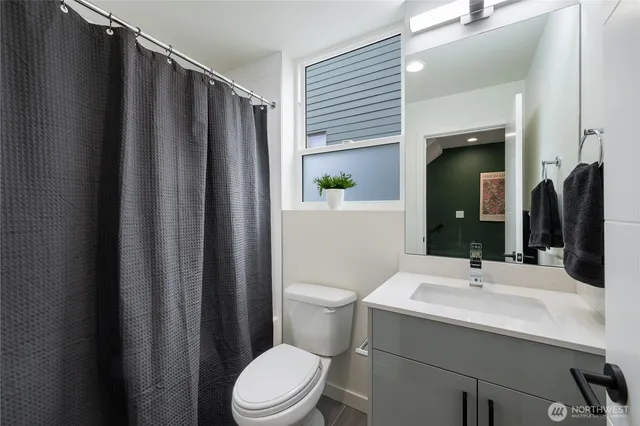 a bathroom with a sink a toilet a mirror and shower curtain