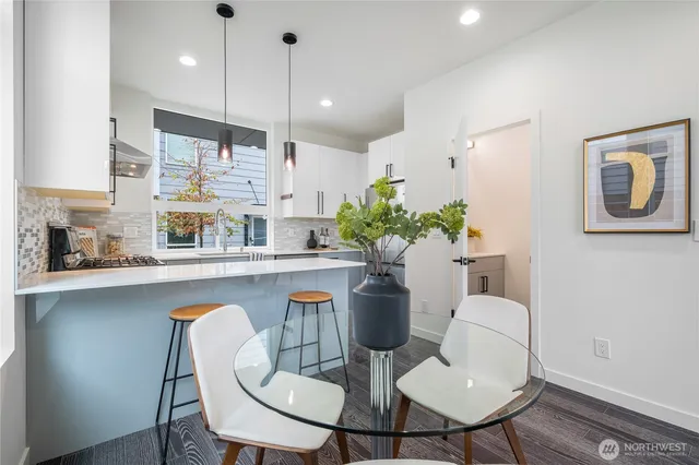 a kitchen with stainless steel appliances kitchen island granite countertop a dining table chairs and a refrigerator