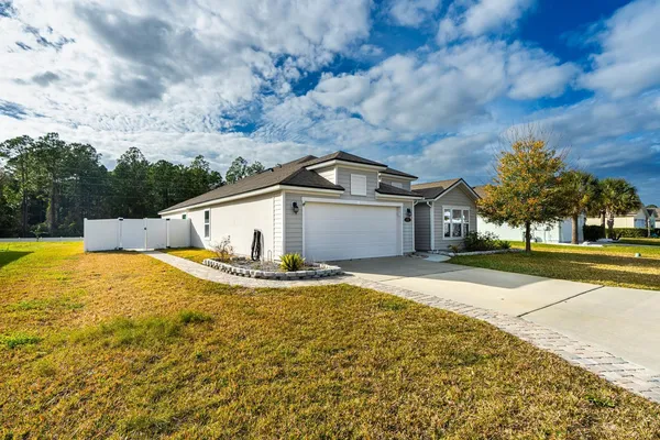 a view of a white house with a yard and large tree