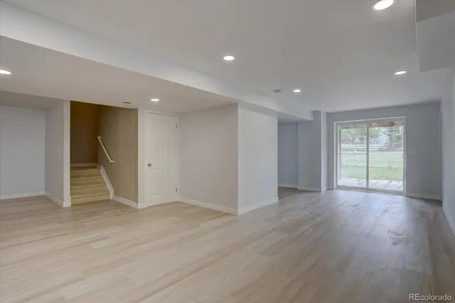 a view of an empty room with wooden floor and window