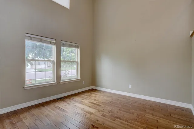 an empty room with wooden floor and windows