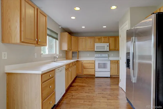 a kitchen with stainless steel appliances granite countertop a refrigerator a sink and a stove