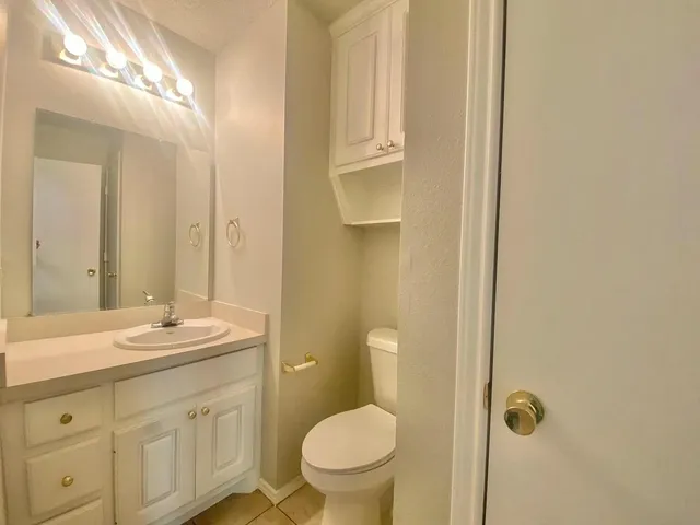 a bathroom with a granite countertop sink a toilet and a mirror