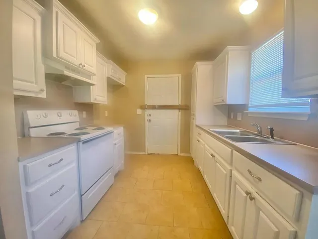 a kitchen with granite countertop white cabinets and white appliances