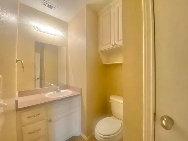 a bathroom with a granite countertop sink a toilet and a mirror