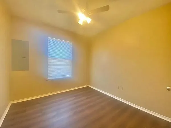 a view of an empty room with wooden floor and a window