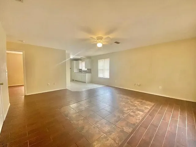 an empty room with wooden floor and windows with curtains