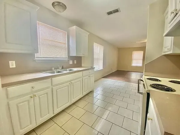 a kitchen with white cabinets a sink a stove and a window