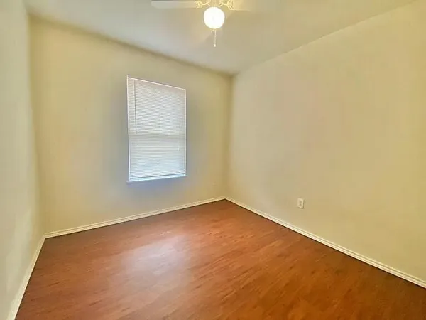 an empty room with a wooden floor and windows