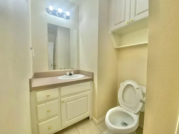 a bathroom with a granite countertop toilet sink and mirror