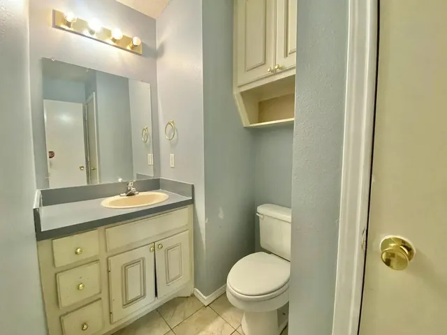 a bathroom with a granite countertop toilet sink and mirror