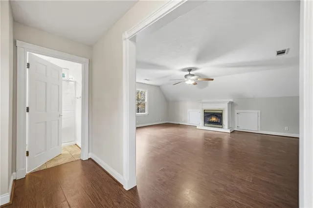an empty room with wooden floor ceiling fan and windows