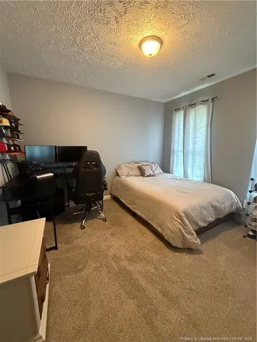 a bedroom with a bed and a computer on the desk