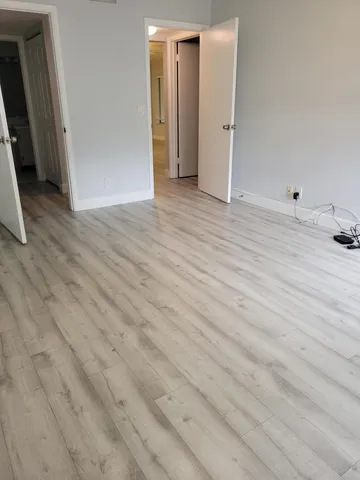 an empty room with wooden floor and bathroom