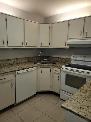 a kitchen with granite countertop white cabinets and stainless steel appliances