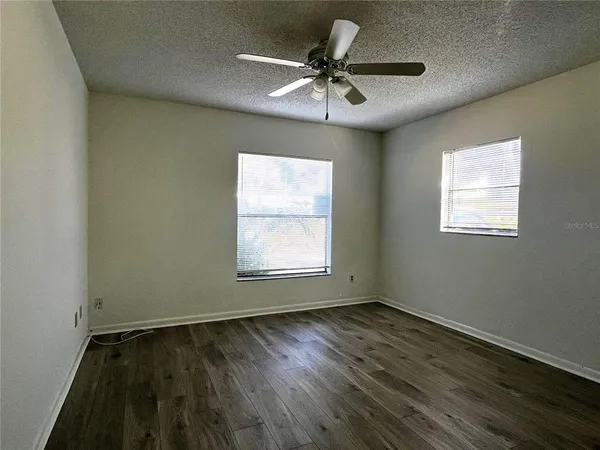 a view of an empty room with a window and wooden floor