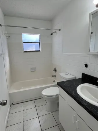 a bathroom with a granite countertop sink a toilet a mirror and bathtub