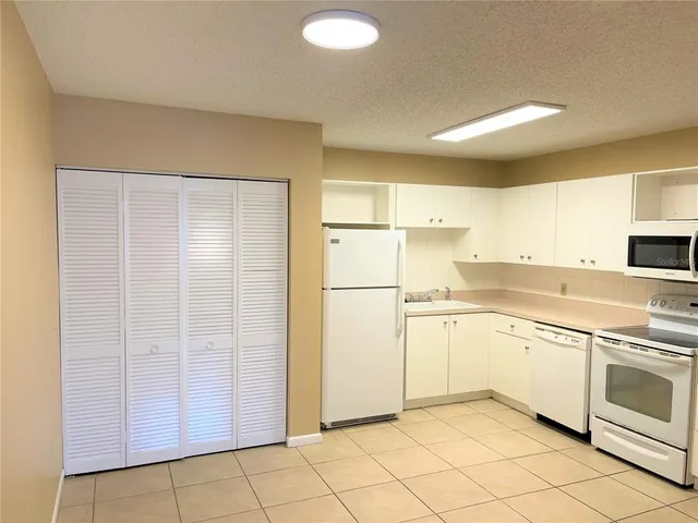 a kitchen with white cabinets and white appliances