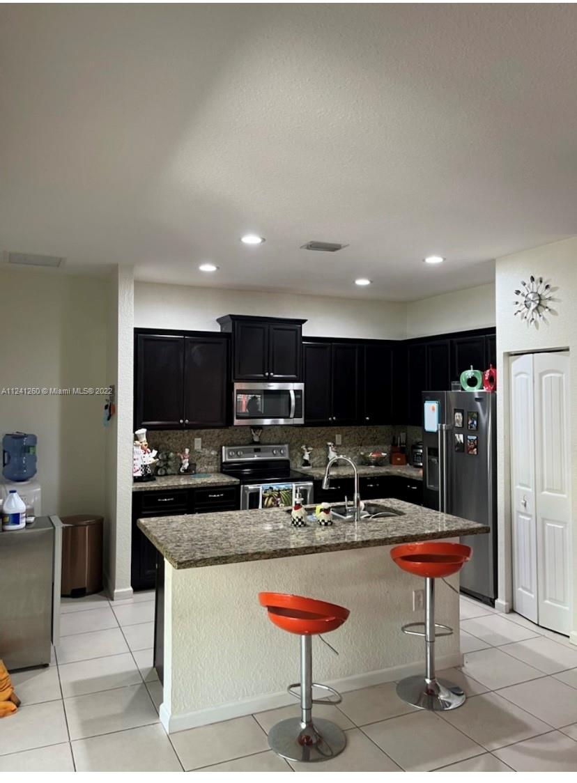 28281 Southwest 128th Place Homestead, FL 33033 - Photo 13 of 39 a kitchen with stainless steel appliances kitchen island granite countertop a table and chairs in it