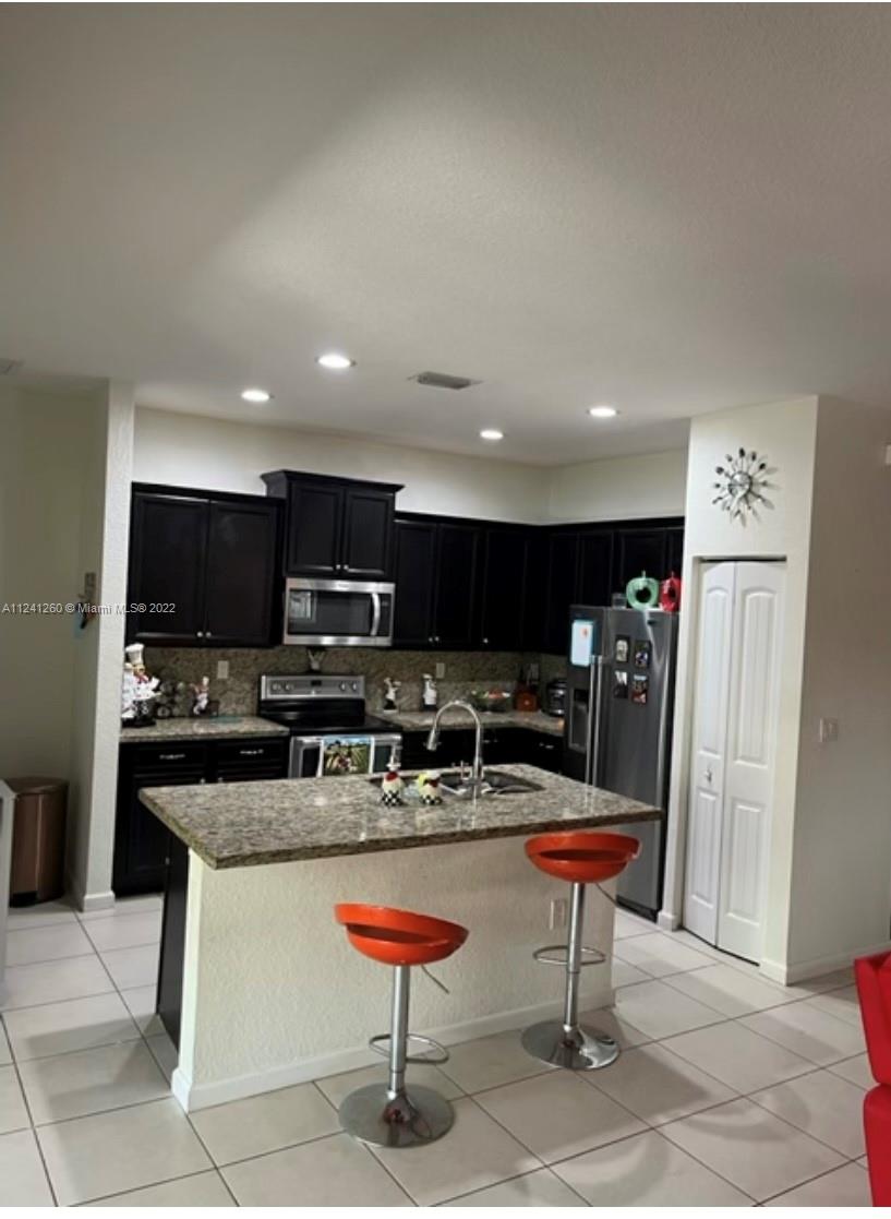28281 Southwest 128th Place Homestead, FL 33033 - Photo 14 of 39 a kitchen with stainless steel appliances kitchen island granite countertop a refrigerator and a stove top oven