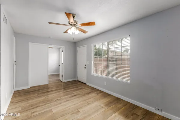 a view of an empty room with wooden floor and a window